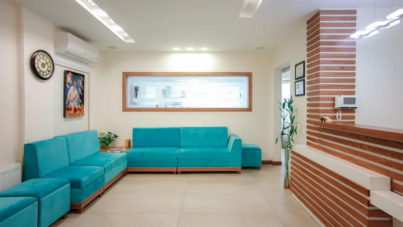 Salle d’attente lumineuse avec sièges turquoise et comptoir de réception