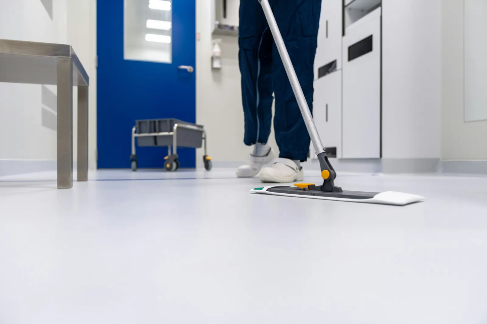 Préposé lavant un plancher à la vadrouille dans un corridor